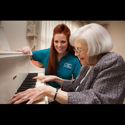 Female Right at Home caregiver watching a senior female play a piano