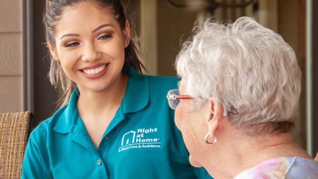 Female carer and senior female talking on a porch. 